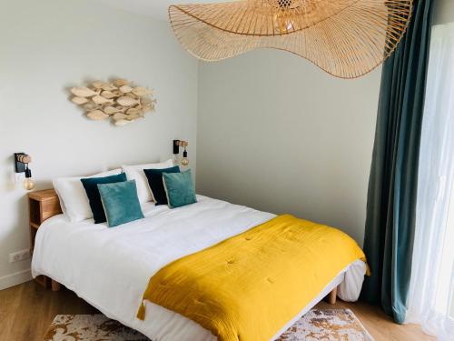 a bedroom with a bed with a yellow and white blanket at Le Clos de Jade - Appt 3 étoiles avec piscine partagée in Pornic