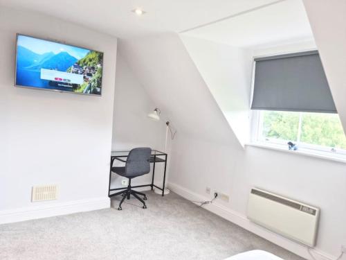 a white room with a chair and a flat screen tv at Hyland Apartment by CityNest in Chelmsford
