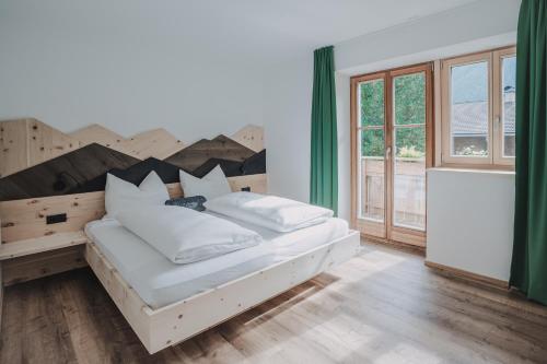 a bedroom with a wooden bed with white pillows at Seeberhof - Urlaub am Bauernhof in San Giacomo