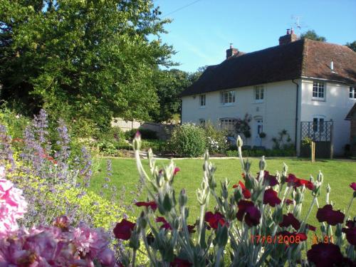 a house and a garden with flowers in the foreground at Bartley Mill Farmhouse in Wadhurst