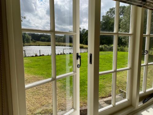 an open window with a view of a field at Bartley Mill Farmhouse in Wadhurst