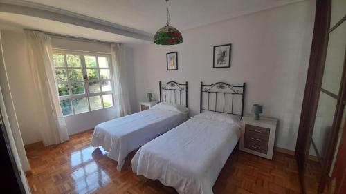 1 dormitorio con 2 camas y ventana en APARTAMENTO EN CANDAS CON GARAJE, en Candás