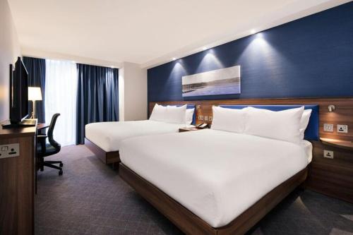 a hotel room with two beds and a desk at Hampton by Hilton Dundee City Centre in Dundee