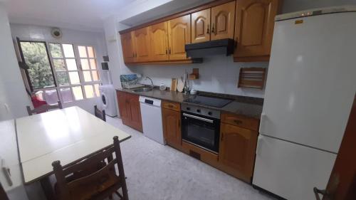 a kitchen with wooden cabinets and a white refrigerator at APARTAMENTO EN CANDAS CON GARAJE in Candás