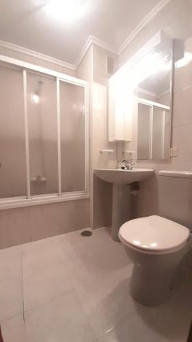 a white bathroom with a toilet and a sink at APARTAMENTO EN CANDAS CON GARAJE in Candás
