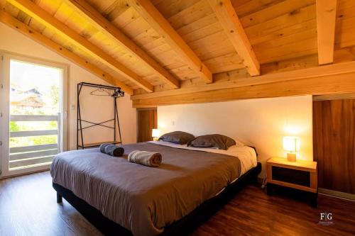 une chambre avec un grand lit avec un plafond en bois dans l'établissement Le Montagny - Conciergerie de la Yaute, à Sallanches