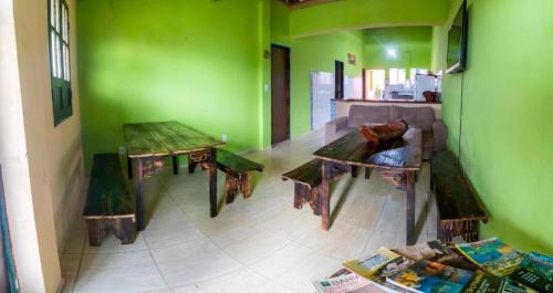 Hostel Zig Zag Suítes في لينكويس: غرفة بجدران خضراء وطاولات خشبية وأريكة