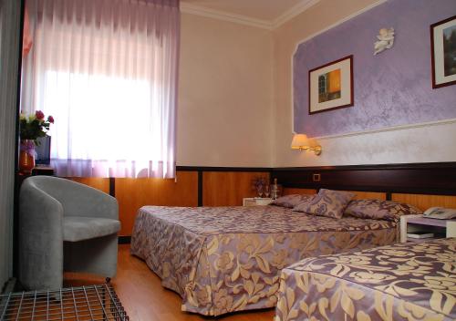 una habitación de hotel con 2 camas y una silla en Benny Hotel, en Catanzaro