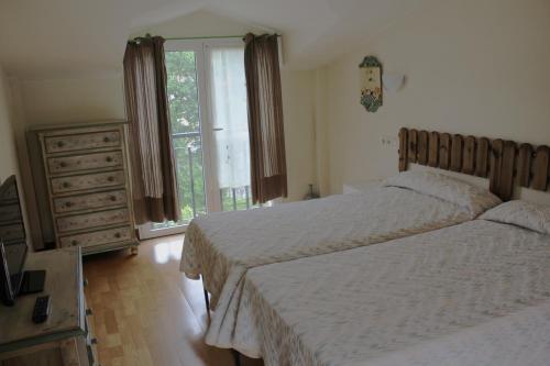 1 dormitorio con 2 camas, vestidor y ventana en Ikaztegietako Ostatua en Icazteguieta