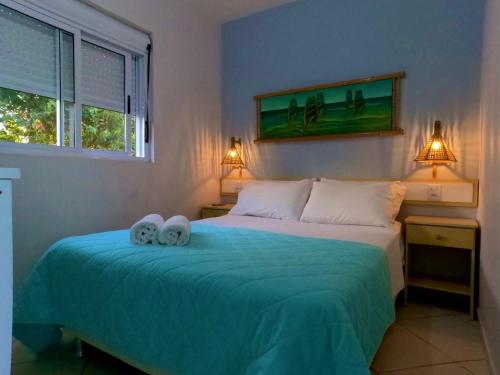 a bedroom with a bed with two towels on it at Pousada Cravo e Canella in Barra de Ibiraquera