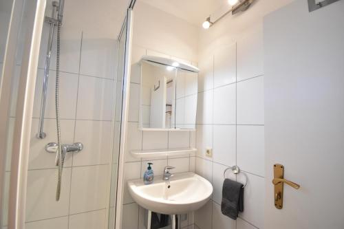 a white bathroom with a sink and a shower at Morgenröte in Norddeich