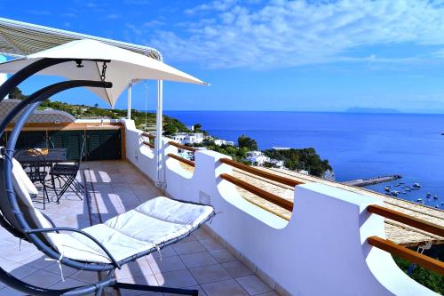Un balcón con sillas, una sombrilla y el océano. en Maridea - La Terrazza en Ponza