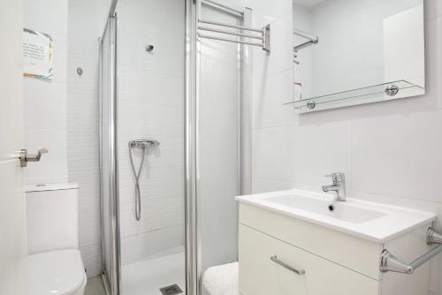 a white bathroom with a sink and a shower at Casa Centro Historico Barbate in Barbate
