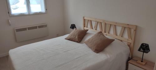 uma cama branca com duas almofadas num quarto em Ici c'est le Marais Poitevin em Ferrières