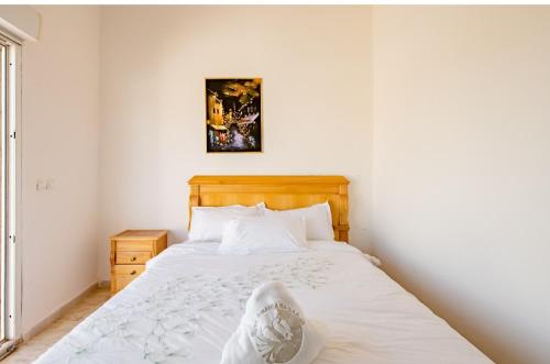 a bedroom with a white bed with a wooden headboard at Gîte équestre Balade plage petit déjeuner au bord de la piscine in Azemmour