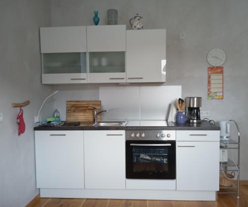 uma cozinha com armários brancos e um forno em Ferienwohnung Haus Knäppen Size M em Oelde