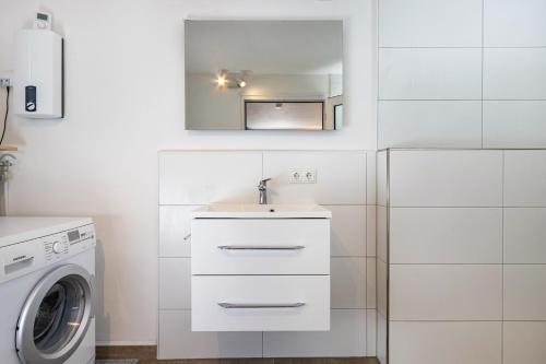 a white bathroom with a sink and a washing machine at Ferienwohnung am Parksee in Bad Bodenteich