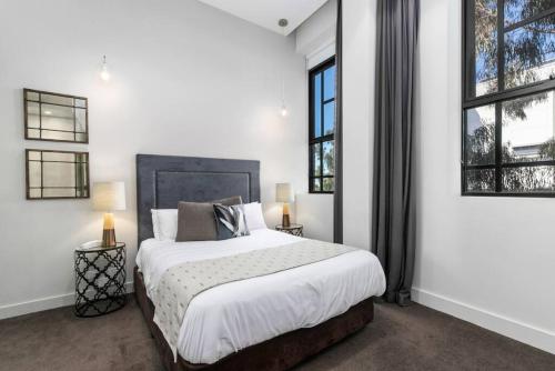 a white bedroom with a large bed and two windows at New York on Moorabool - Free Wi-Fi in Geelong