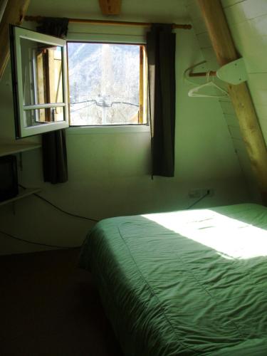 a bedroom with a green bed and a window at Complejo de Cabañas Tierra de Luna in Potrerillos