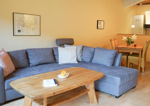 sala de estar con sofá azul y mesa de madera en Ferienhof Landlord, en Fehmarn