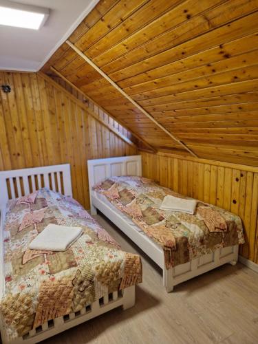 two beds in a room with wooden walls at Poarta Zaganului Cheia in Cheia