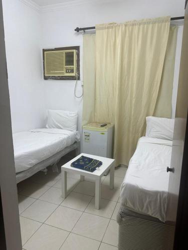 a room with two beds and a table in it at فندق النجمتين الفضية in An Naqāʼ