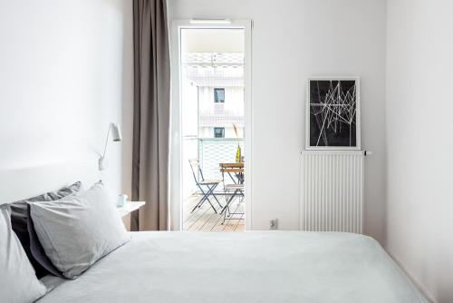 a white bedroom with a bed and a balcony at Apartamenty City Tower od WroclawApartament-pl in Wrocław