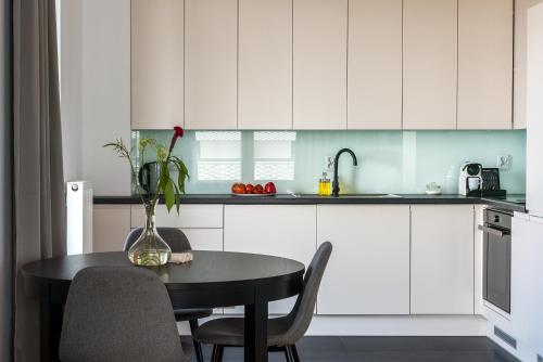 a kitchen with white cabinets and a table with chairs at Apartamenty City Tower od WroclawApartament-pl in Wrocław