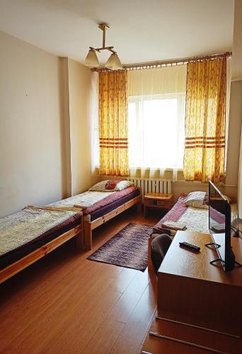 Habitación con 2 camas y escritorio con ordenador. en Ratuszowy en Włocławek