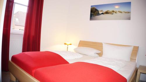 Schlafzimmer mit einem roten und weißen Bett und einem Fenster in der Unterkunft Jana in Norddeich