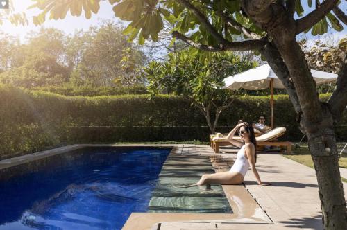 a woman in a white dress sitting next to a swimming pool at The Oberoi Rajvilas Jaipur in Jaipur