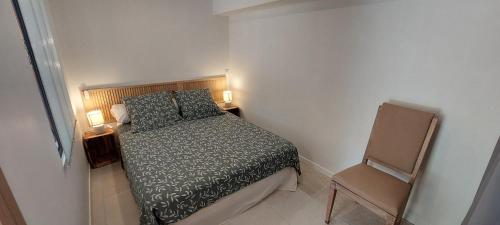 um pequeno quarto com uma cama e uma cadeira em MyLuberon-Appartement au pied du Luberon em Lauris