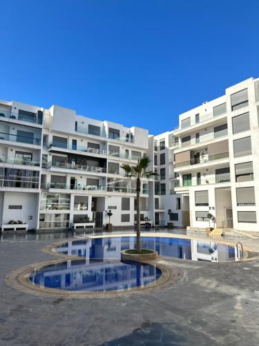 Luxury Apartment in Agadir Bay في أغادير: عمارة سكنية كبيرة امامها نخلة