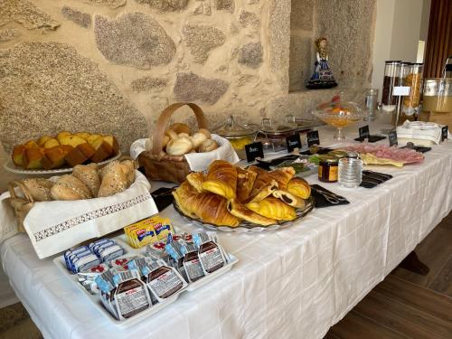 une table avec différents types de pain et d'autres aliments dans l'établissement Alminhas da Mindua - Unique Experiences by LuxiStay, à Vitorino dos Piães