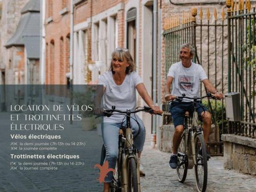 a man and a woman riding bikes down a street at Chimay : La Chambre Dorée de la Grand Place in Chimay