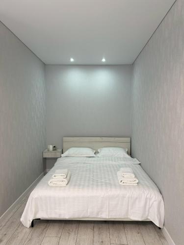 sypialnia z białym łóżkiem i 2 ręcznikami w obiekcie Apart Inn - Апарт Отель w mieście Uralsk