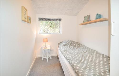 a small bedroom with a bed and a window at Nice Home In Hvide Sande With Kitchen in Hvide Sande