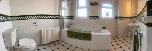 a bathroom with a tub and a toilet and a sink at Alexandria House in Donaghadee