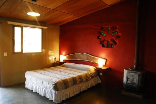 1 dormitorio con 1 cama en una pared roja en TrinidadTraslasierra en Las Rabonas