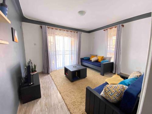 sala de estar con sofá azul y TV en Rozy homes Jinja, en Jinja