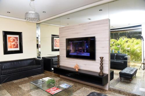 uma sala de estar com uma televisão de ecrã plano na parede em Cedro Hotel em Londrina