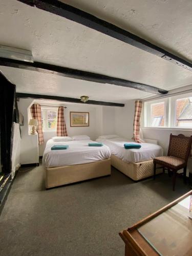 a bedroom with two beds and a chair at The King's Lodge Hotel in Kings Langley