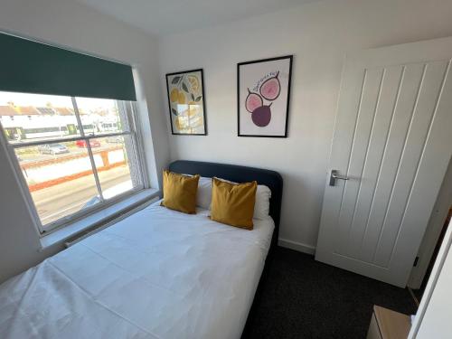 a bedroom with a bed with yellow pillows and a window at Littlehampton House - 4 bedroom house sleeps 8 in Littlehampton