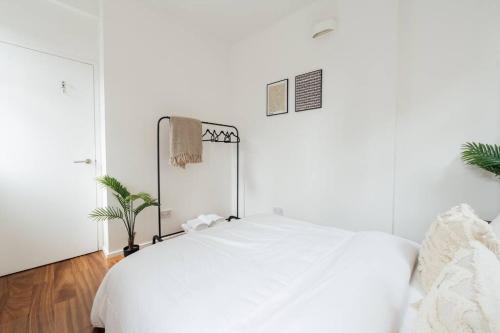 a white bedroom with a white bed and a plant at Modern 1BD Flat -Stoke Newington in London
