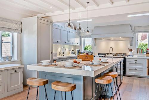a kitchen with white cabinets and a large island with stools at Bedgebury Oast by Bloom Stays in Goudhurst