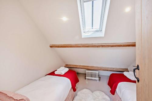 two beds in a small room with a window at Bedgebury Oast by Bloom Stays in Goudhurst