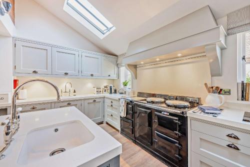 a kitchen with white cabinets and a sink and a stove at Bedgebury Oast by Bloom Stays in Goudhurst