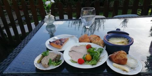 una mesa con platos de comida y una copa de vino en Magnifique bateau maison, en Ouistreham