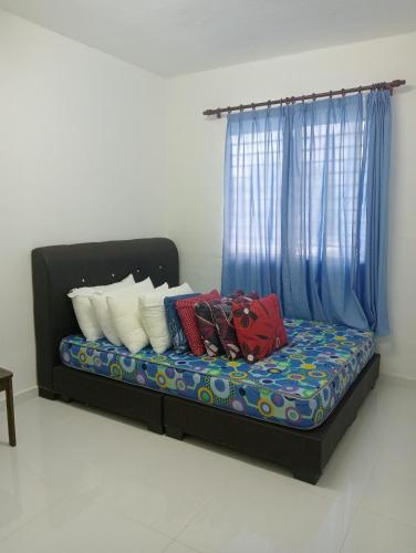 1 cama con cortina azul y algunas almohadas en SERI BAKAWALI HOMESTAY en Rawang