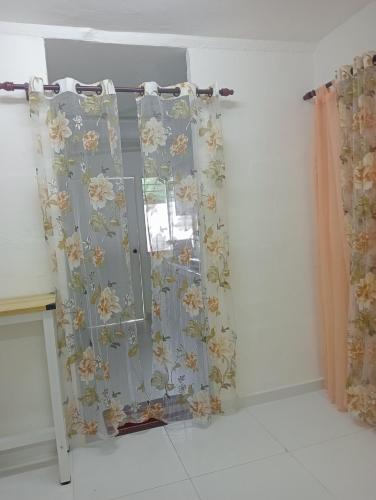 Una ventana con cortinas con flores. en SERI BAKAWALI HOMESTAY en Rawang